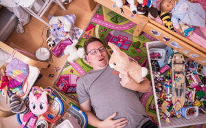 Etäisä Tomi Laaksonen makaa lastenhuoneen lattialla lelujen keskellä ja sylissään pehmolelu